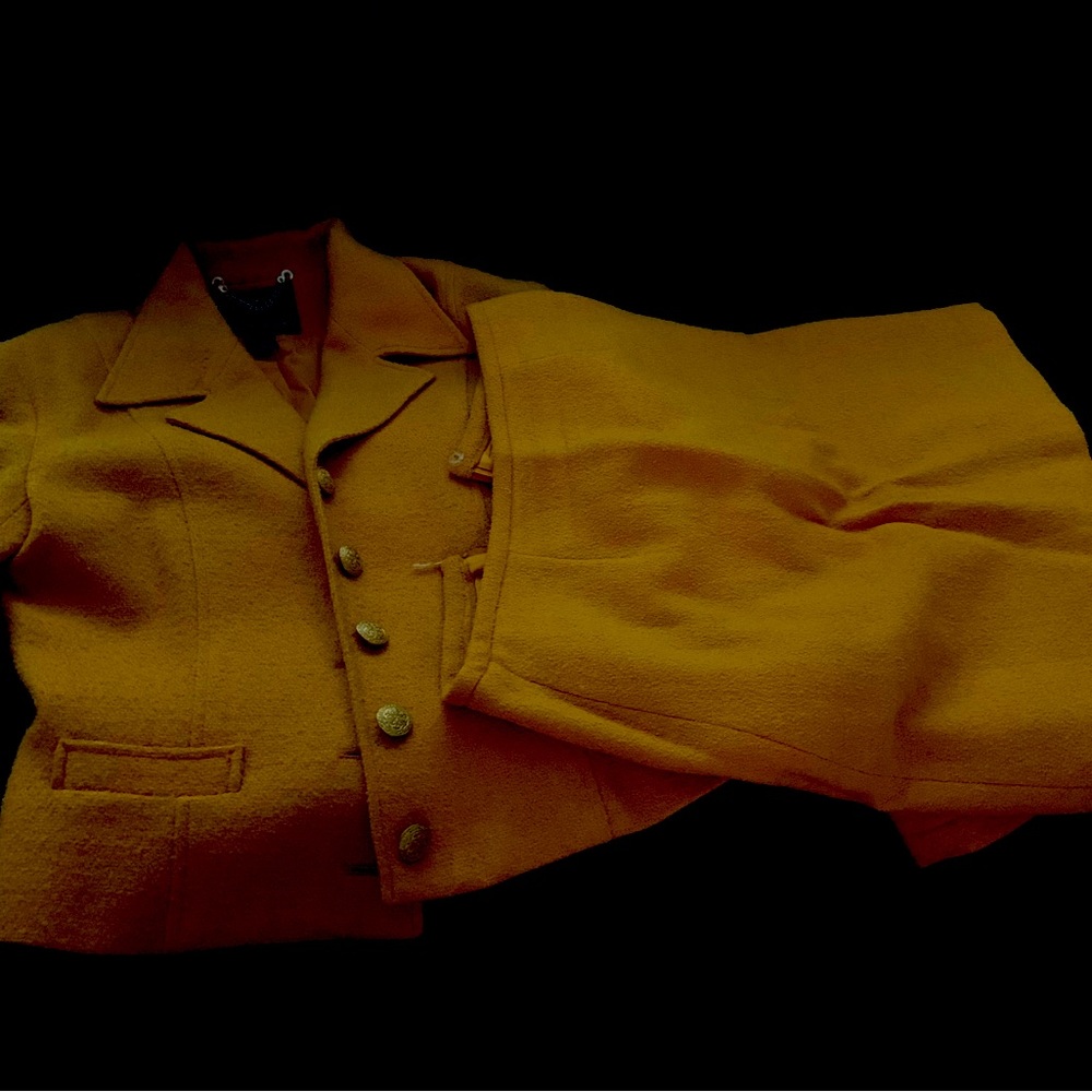 Gold suit jacket has gold button and skirt above knee